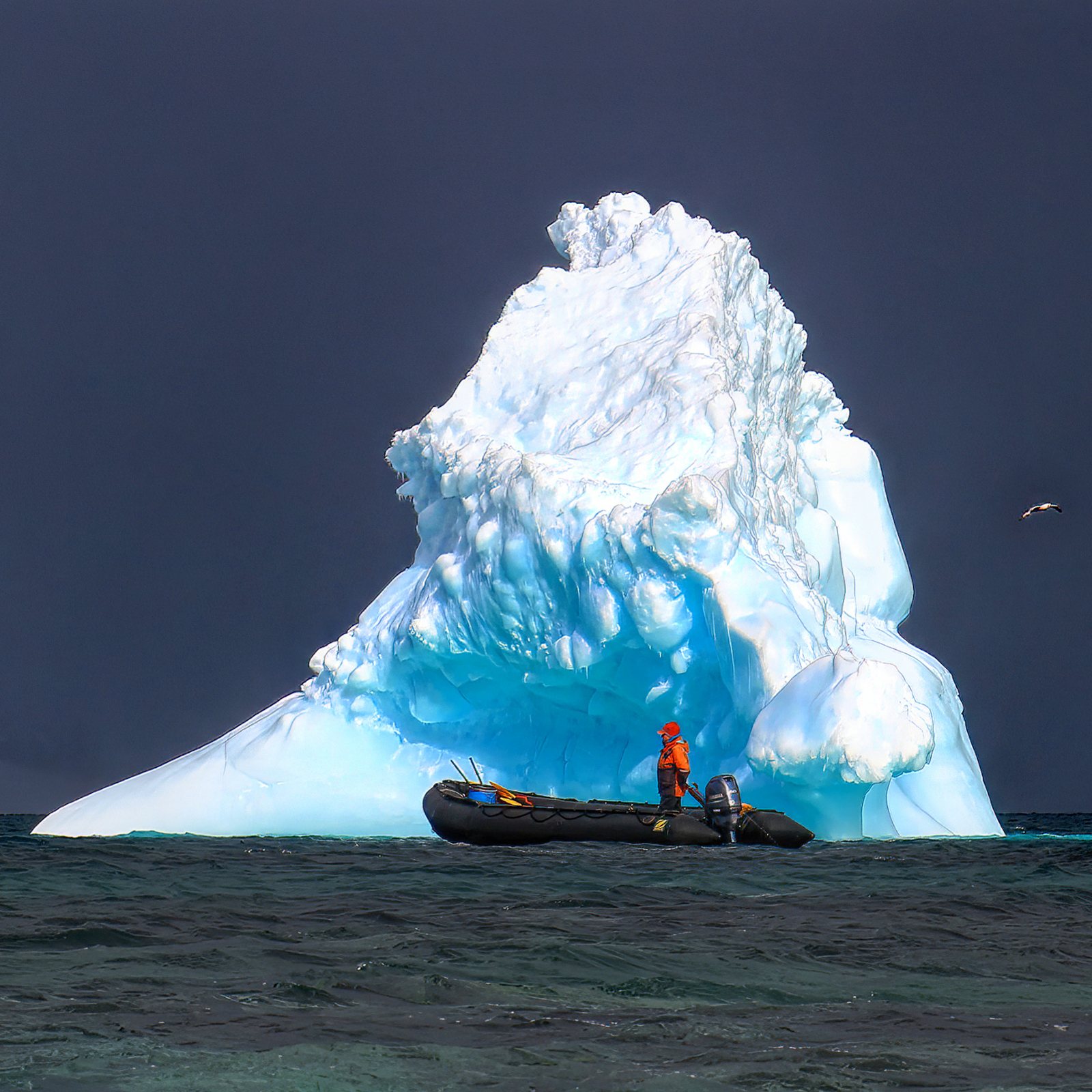 Zodiac beneath a towering iceberg, Antarctic Peninsula