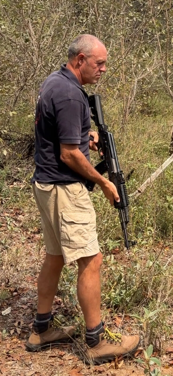 James Kenning holding an AK-47 rifle during target practice in the bush